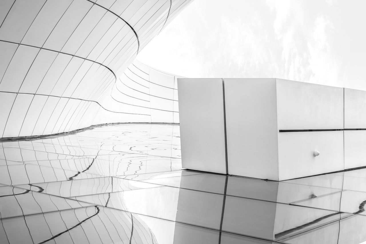 who-we-are Sleek futuristic architecture in black and white with reflective surfaces.