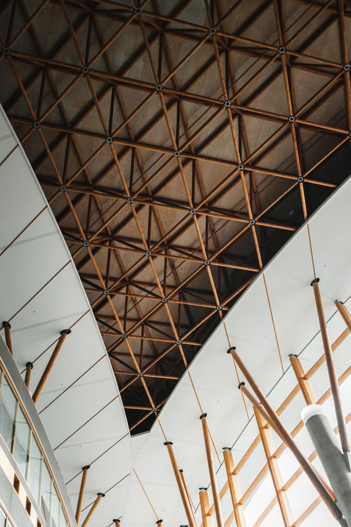 get-in-touch Elegant modern ceiling featuring a geometric wooden lattice structure in an urban setting.