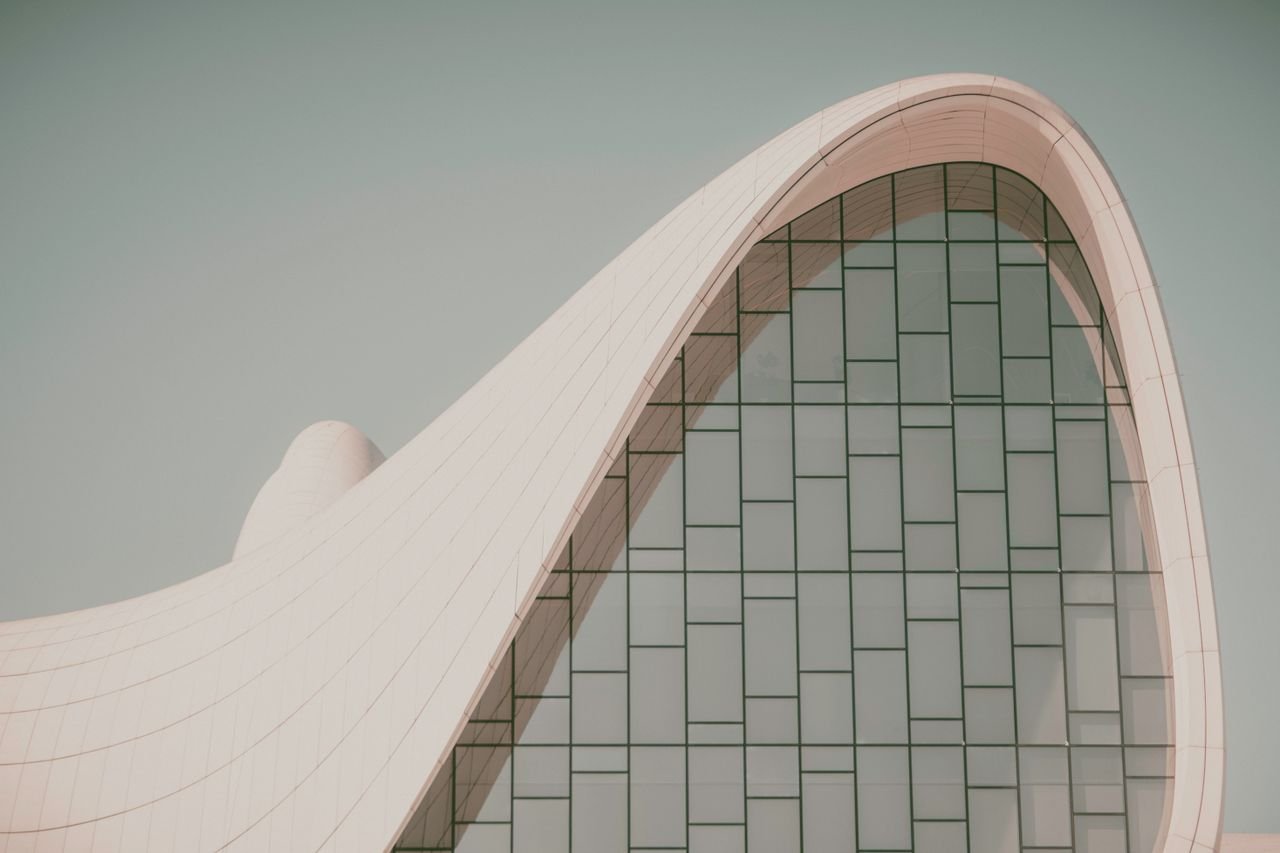 why-choose-us Futuristic curved building with modern glass design, showcasing innovative architectural elements.