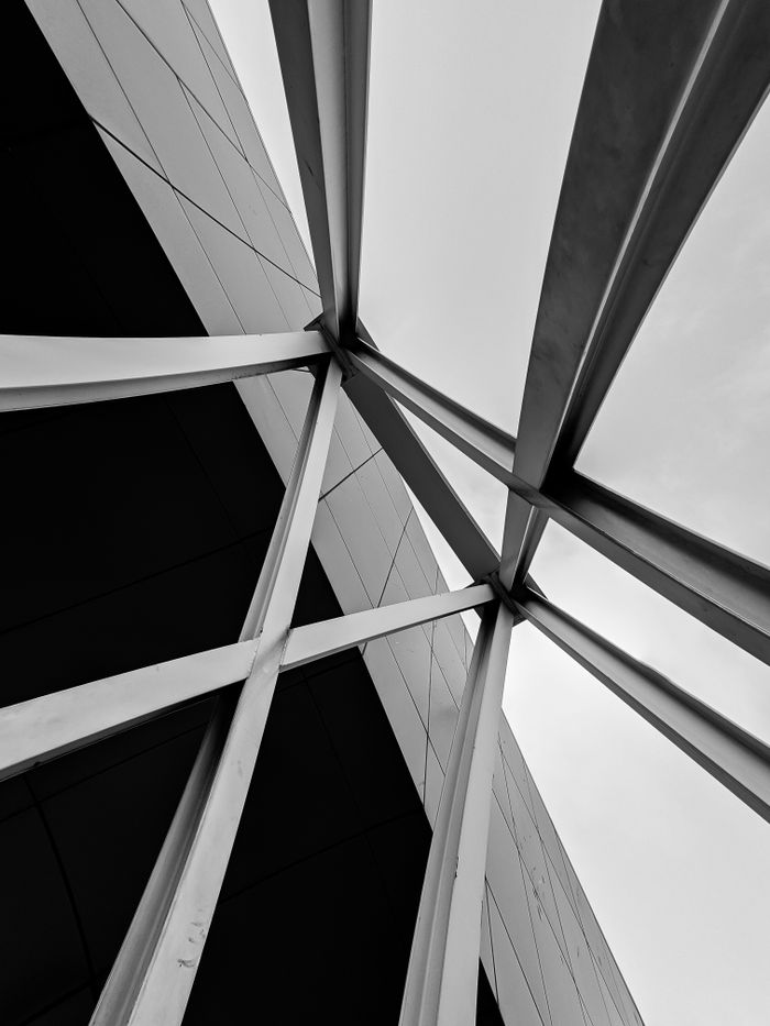 services-04 Black and white view of modern architectural beams forming a geometric pattern.