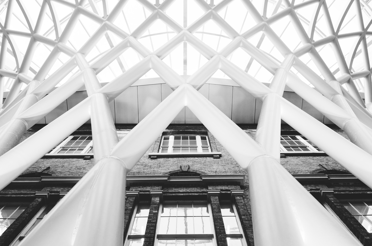 services-02 Black and white photo of the intricate modern roof structure at King's Cross Station in London, England.