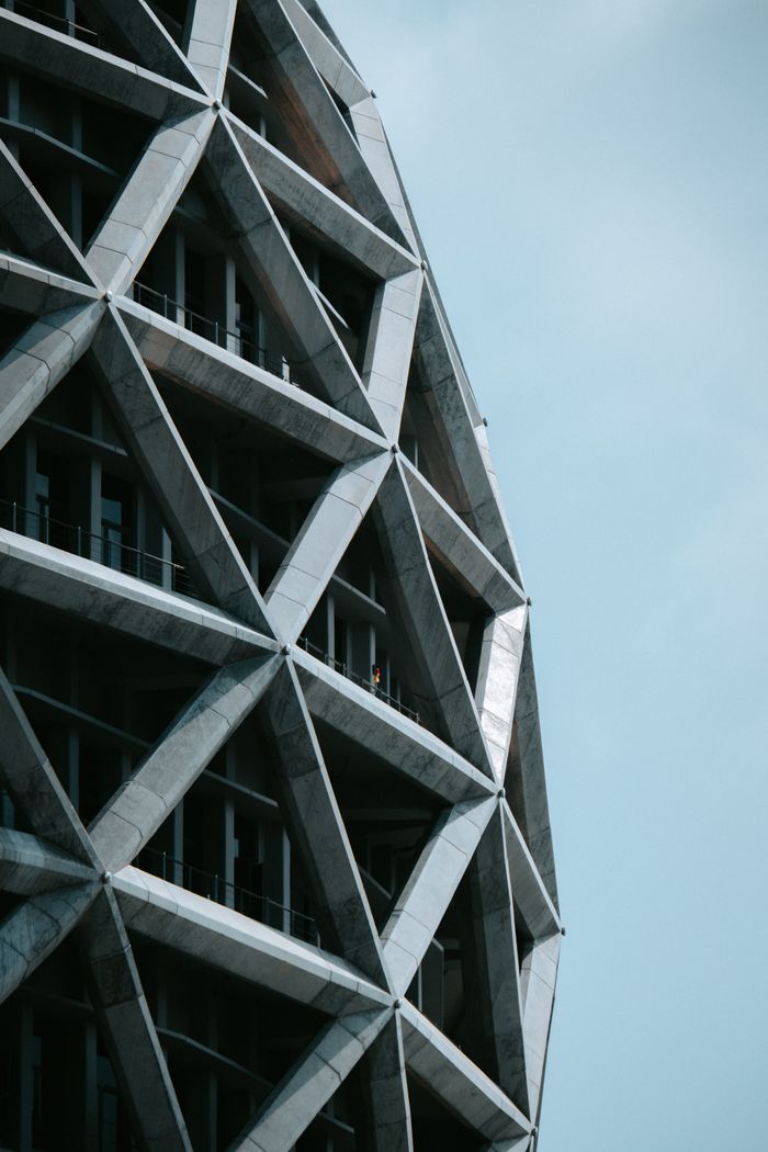 Modern building facade with geometric patterns and concrete elements against a clear sky.
